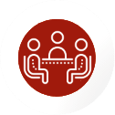 Red circle icon depicting a group meeting among counsellors seated around a table with two individuals in chairs, representing guidance and support for students pursuing nursing Ausbildung in Germany, enrolling in a nursing course in Germany, or applying for a nursing job in Germany.